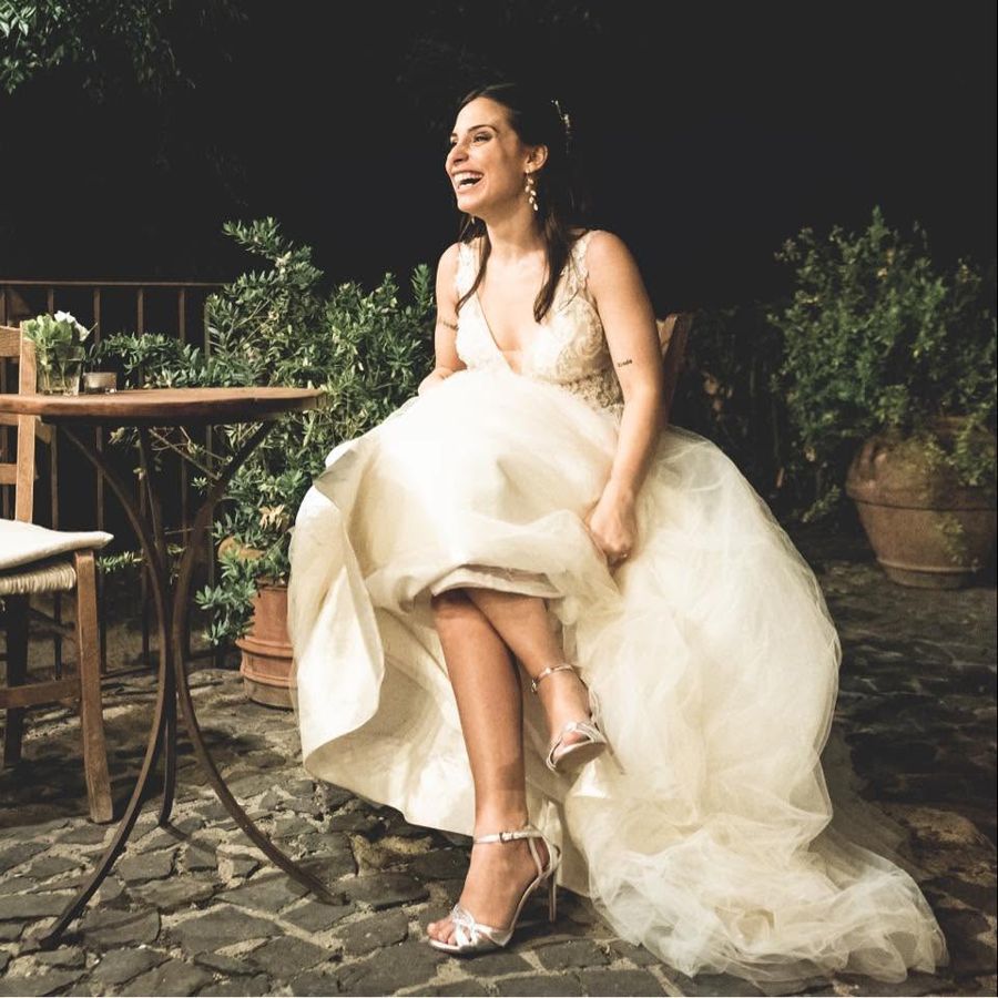 Giulia in abito da sposa, seduta in giardino, ride
